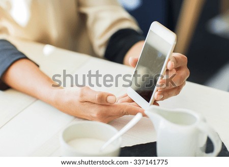 people, holidays, technology and lifestyle concept - close up of women with smartphone at restaurant