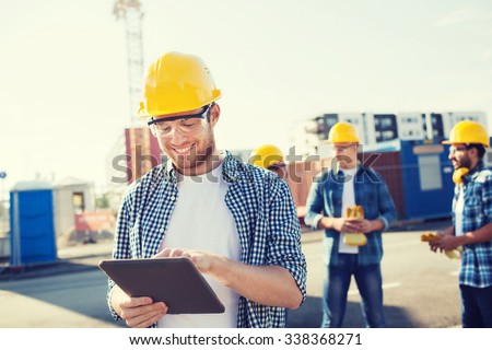 business, building, teamwork, technology and people concept - group of smiling builders in hardhats with tablet pc computer outdoors