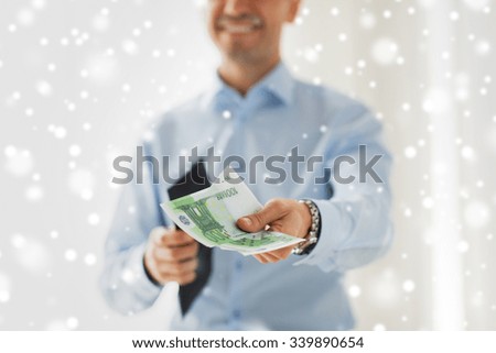 people, business, finances and money concept - close up of businessman hands holding open wallet with euro cash over snow effect