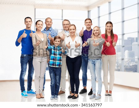 gesture, family, generation, real estate and people concept - group of smiling men and women showing thumbs up over empty apartment or office room background