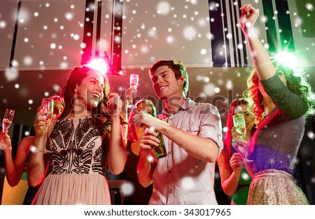 new year party, holidays, celebration, nightlife and people concept - smiling friends clinking glasses of non-alcoholic champagne and beer in club and snow effect