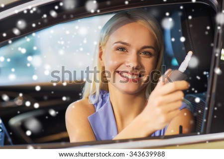 auto business, car sale, consumerism and people concept - happy woman taking car key from dealer in auto show or salon over snow effect