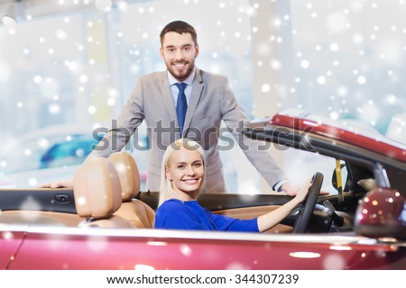auto business, car sale, consumerism and people concept - happy couple buying cabrio car in auto show or salon over snow effect