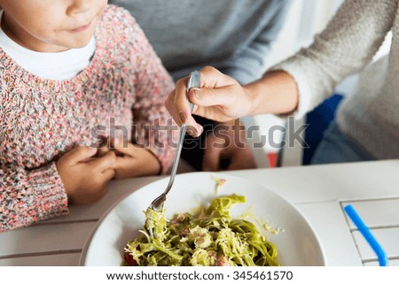 family, parenthood, food and people concept - close up of family eating pasta for dinner at restaurant or cafe