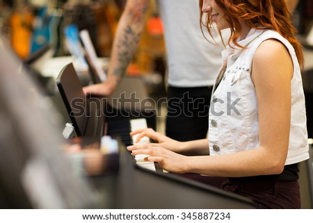 music, sale, people, musical instruments and entertainment concept - close happy man and woman playing piano at music store
