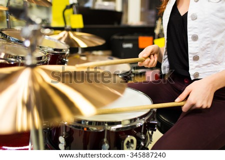 music, sale, people, musical instruments and entertainment concept - close up of female musician playing cymbals at music store