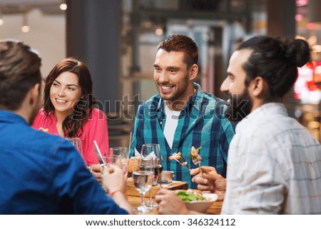 leisure, food and drinks, people and holidays concept - happy friends having dinner at restaurant