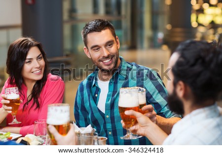 leisure, eating, food and drinks, people and holidays concept - smiling friends having dinner and drinking beer at restaurant or pub