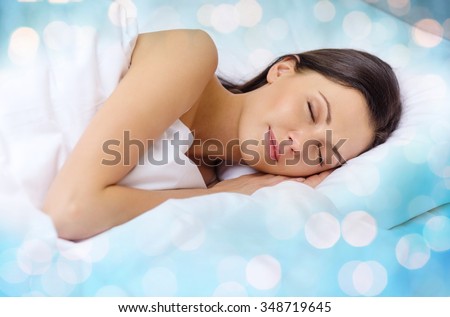 rest and comfort concept - beautiful woman sleeping in bed over blue lights background