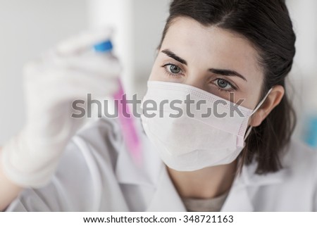 science, chemistry, biology, medicine and people concept - close up of young female scientist holding tube with sample making and test or research in clinical laboratory
