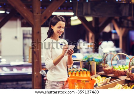 happy woman with food basket and notepad in market