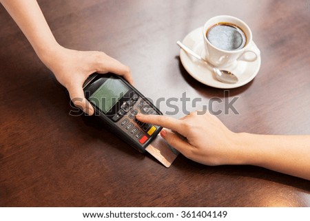 close up of hands with credit card reader at cafe