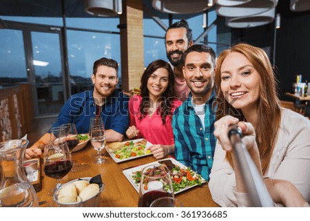 friends picturing by selfie stick at restaurant