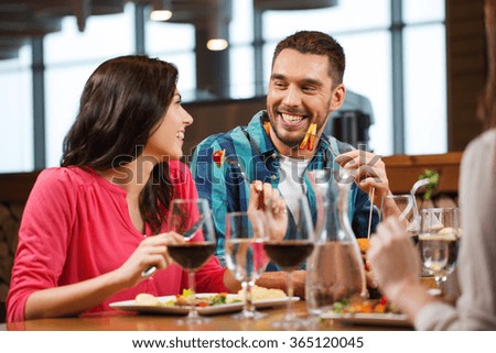 happy couple with friends eating at restaurant