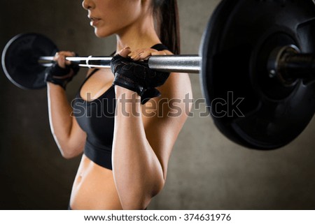 sport, fitness, bodybuilding, weightlifting and people concept - close up of young woman with barbell flexing muscles in gym