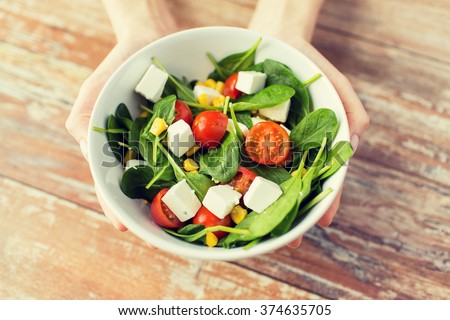 healthy eating, dieting and people concept - close up of young woman hands showing salad bowl at home