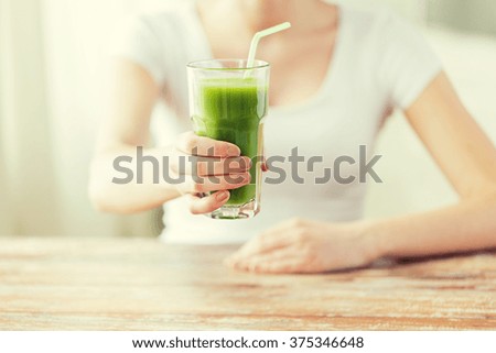 healthy eating, food, diet, detox and people concept - close up of woman hands with green juice on wooden table