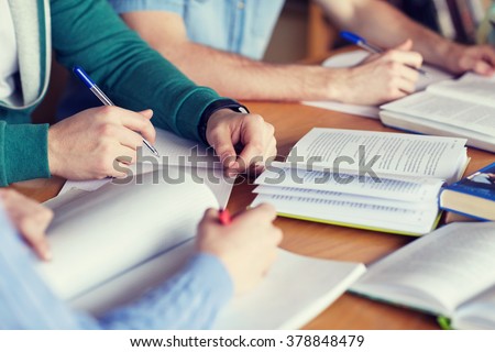 people, learning, education and school concept - close up of students hands with books or textbooks writing to notebooks