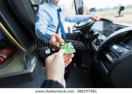 transport, tourism, road trip and people concept - close up of bus driver taking ticket or plastic card from passenger