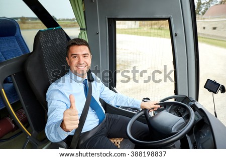 transport, tourism, road trip and people concept - happy driver driving intercity bus and snowing thumbs up