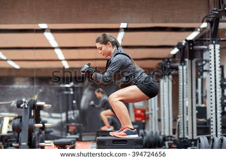 fitness, sport, exercising and people concept - woman doing squats on platform in gym