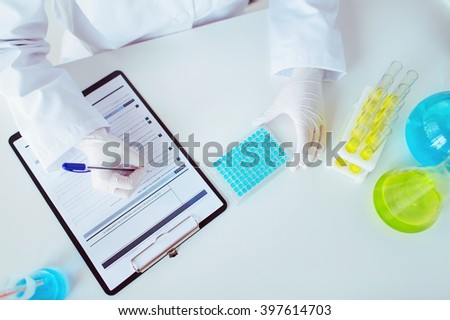 science, chemistry, biology, medicine and people concept - close up of scientist with test sample making research in clinical laboratory