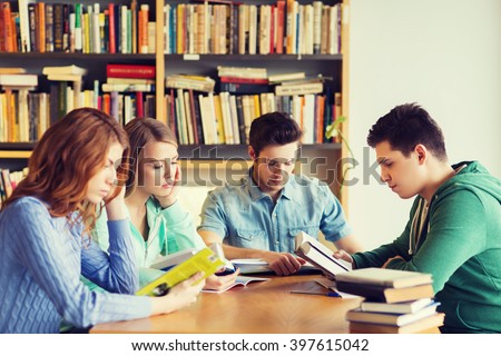 people, knowledge, education and school concept - group of students reading books and preparing to exam in library