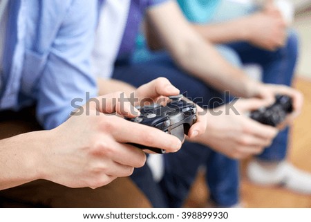 friendship, technology, games and home concept - close up of male friends playing video games at home