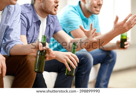 friendship, leisure, people and alcohol concept - close up of happy male friends drinking beer and watching tv at home