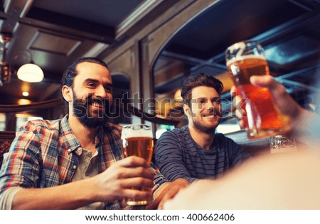 people, leisure, friendship and and bachelor party concept - happy male friends drinking beer at bar or pub