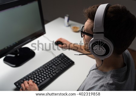 technology, gaming, entertainment, let\'s play and people concept - close up of young man in headset and glasses with pc computer playing game at home and streaming playthrough or walkthrough video
