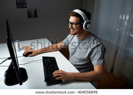 technology, gaming, entertainment, let\'s play and people concept - happy young man in headset and glasses with pc computer playing game at home and streaming playthrough or walkthrough video