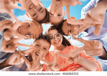 childhood, fashion, friendship and people concept - happy smiling children showing peace hand sign and standing in circle over blue sky and clouds background