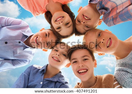 childhood, fashion, summer, friendship and people concept - happy smiling children faces over blue sky and clouds background
