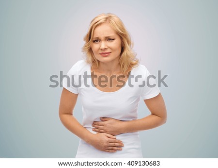 people, healthcare and problem concept - unhappy woman suffering from stomach ache over gray background