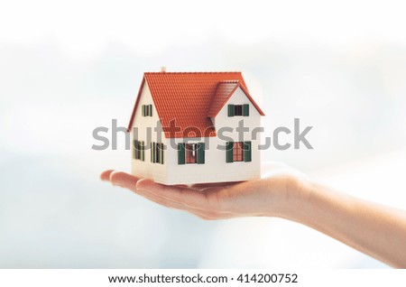 architecture, building, construction, real estate and property concept - close up of hands holding house or home model