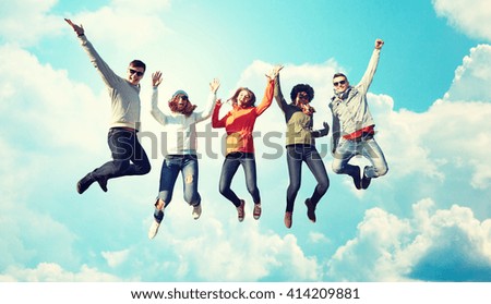 people, freedom, happiness and teenage concept - group of happy friends in sunglasses jumping high over blue sky and clouds background