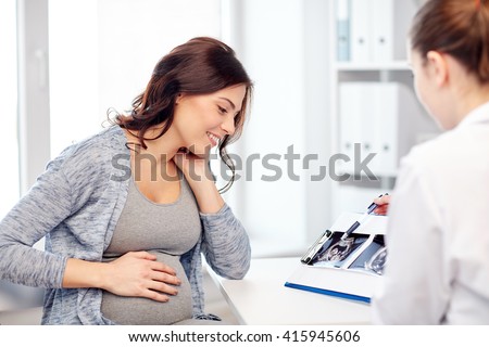pregnancy, gynecology, medicine, health care and people concept - gynecologist doctor showing ultrasound image on clipboard to pregnant woman at hospital