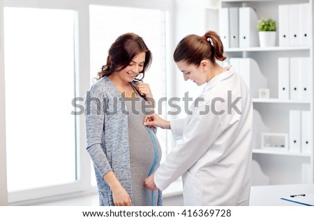 pregnancy, gynecology, medicine, health care and people concept - gynecologist doctor with centimeter tape measuring pregnant woman tummy at hospital