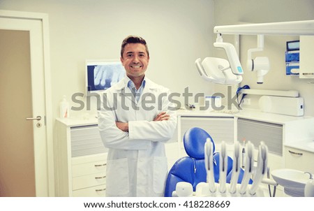 people, medicine, stomatology and healthcare concept - happy middle aged male dentist in white coat at dental clinic office