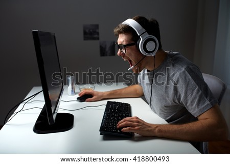 technology, gaming, entertainment, let\'s play and people concept - angry screaming young man in headset with pc computer playing game at home and streaming playthrough or walkthrough video
