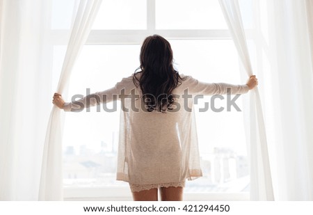 people and morning concept - close up of happy woman opening window curtains at home