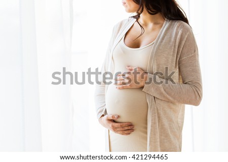 pregnancy, motherhood, people and expectation concept - close up of pregnant woman with big belly looking to window