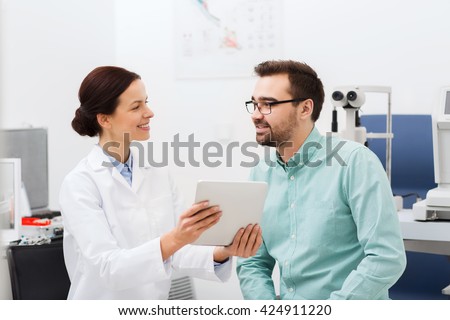 health care, medicine, people, eyesight and technology concept - female optician in glasses with tablet pc computer and man at eye clinic or optics store