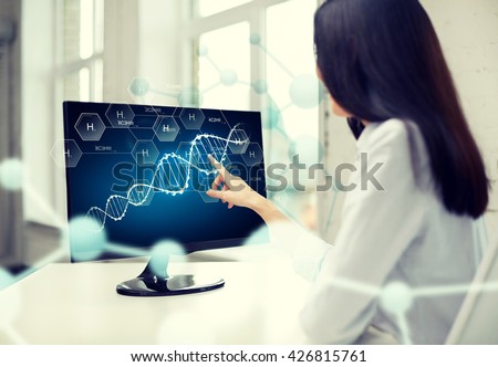 people, technology, biology, genetics and science concept - close up of woman pointing finger to dna molecule on computer monitor in office
