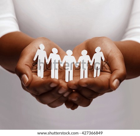 community, unity and charity concept - african american female hands holding and showing paper people team