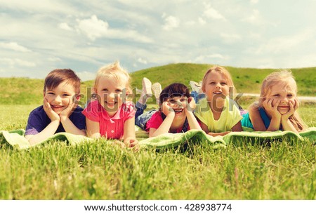summer, childhood, leisure and people concept - group of happy kids lying on blanket or cover outdoors