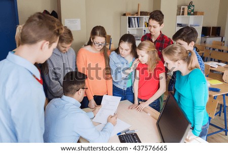 education, school, learning, teaching and people concept - group of students and teacher checking tests at school