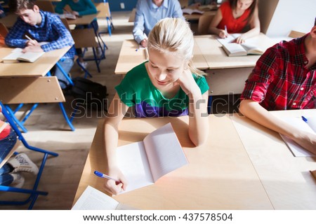 education, learning and people concept - group of students with notebooks and books writing school test