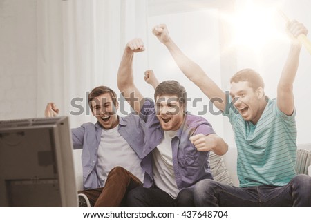 friendship, sports and entertainment concept - happy male friends with vuvuzela watching sports on tv